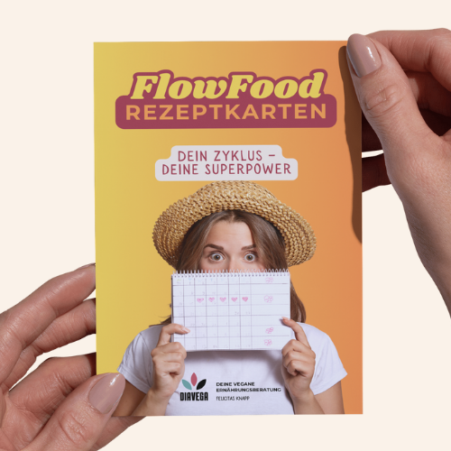 Frau hält Rezeptkarten mit dem Titel "FlowFood" und lächelt, trägt einen Strohhut.