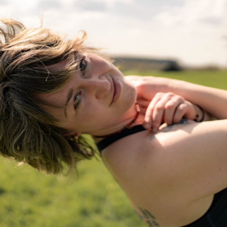 Felicitas Knapp – eine weibliche Person mit kurzen, lockigen Haaren in beige Weste, lächelnd vor hellem Hintergrund.